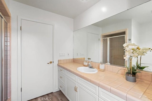 bathroom with vanity, a shower stall, and wood finished floors