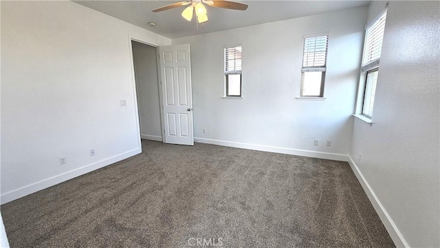 unfurnished room with dark colored carpet, baseboards, and ceiling fan