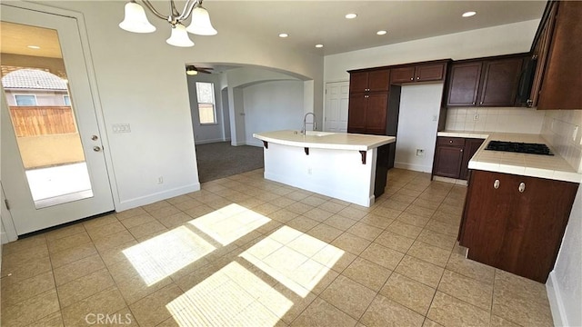 kitchen featuring a sink, backsplash, recessed lighting, arched walkways, and dark brown cabinetry