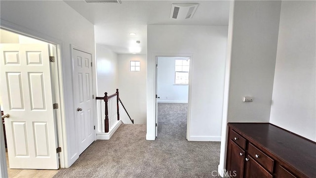 corridor with baseboards, an upstairs landing, visible vents, and light carpet