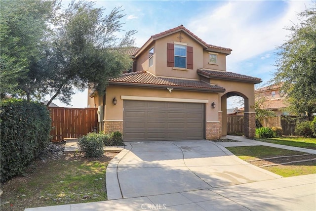 mediterranean / spanish house with brick siding, driveway, and fence