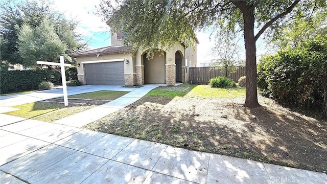 view of front of house with stucco siding, driveway, fence, a garage, and brick siding