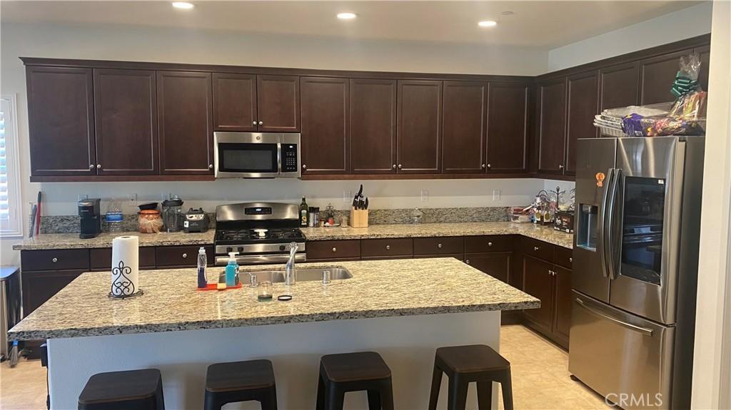 kitchen featuring dark brown cabinetry, recessed lighting, appliances with stainless steel finishes, and a breakfast bar area