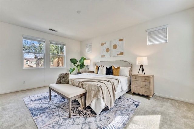 bedroom with baseboards, visible vents, and light carpet