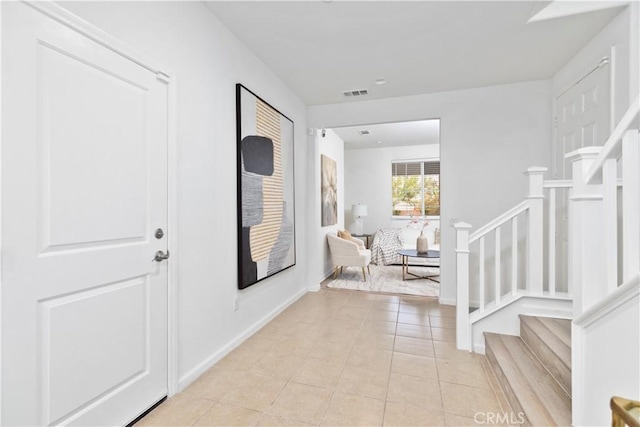 foyer entrance featuring light tile patterned floors, stairway, baseboards, and visible vents