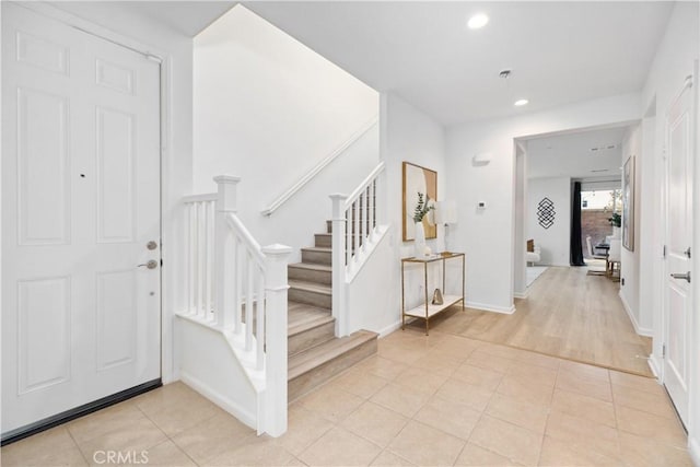 foyer featuring light tile patterned floors, baseboards, stairs, and recessed lighting