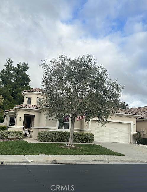 view of front facade with stucco siding, a tiled roof, concrete driveway, and an attached garage