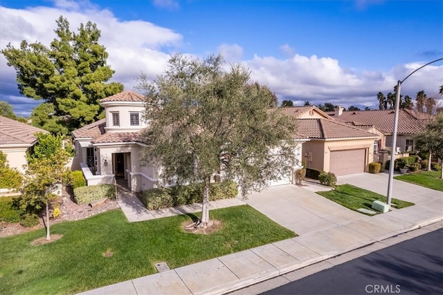 mediterranean / spanish house featuring a tile roof, an attached garage, concrete driveway, and stucco siding