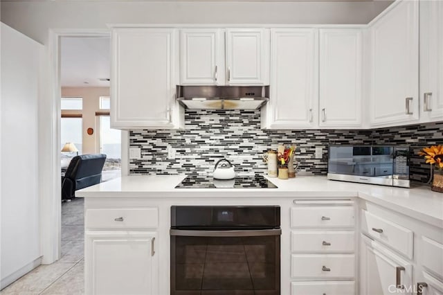 60125 Carrizo Rd, Mountain Center, CA 92561 - kitchen with white cabinetry, black appliances, backsplash, under cabinet range hood, and light countertops