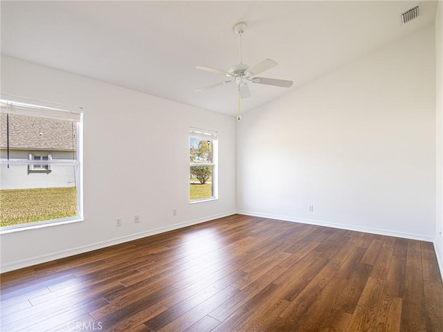 spare room with visible vents, lofted ceiling, dark wood-type flooring, and baseboards