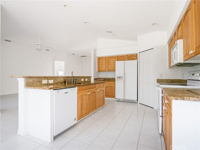 kitchen with an island with sink, white appliances, stone countertops, a ceiling fan, and a sink