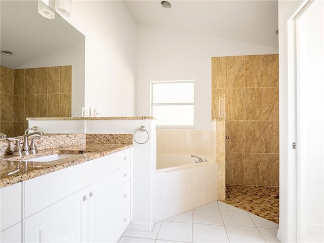 bathroom featuring tile patterned flooring, walk in shower, lofted ceiling, a garden tub, and vanity