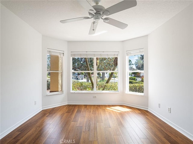 empty room with a textured ceiling, a ceiling fan, baseboards, and hardwood / wood-style flooring