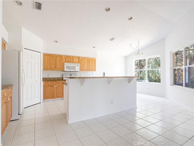 kitchen with visible vents, a breakfast bar, vaulted ceiling, light tile patterned floors, and white appliances