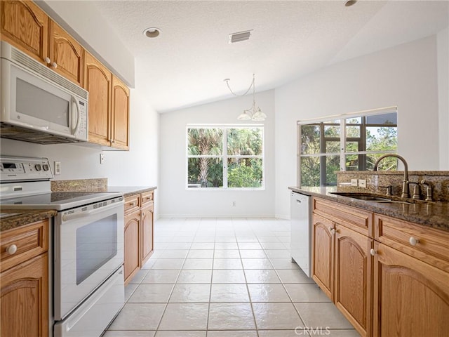 kitchen with visible vents, a sink, dark stone counters, white appliances, and lofted ceiling