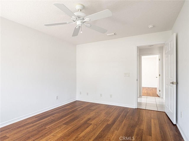 unfurnished room with hardwood / wood-style floors, baseboards, visible vents, and ceiling fan