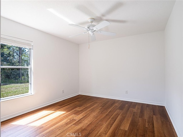 spare room with dark wood finished floors, a ceiling fan, and baseboards