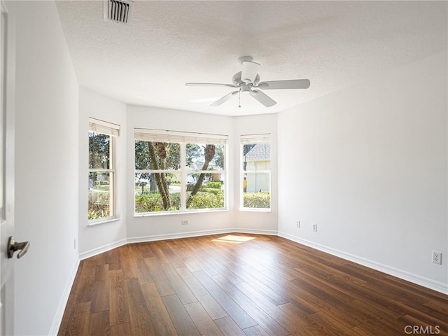 unfurnished room with visible vents, baseboards, wood finished floors, a textured ceiling, and a ceiling fan