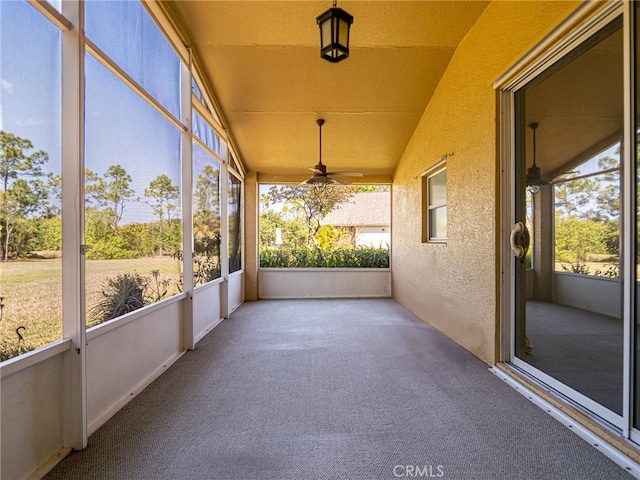 unfurnished sunroom with a ceiling fan and vaulted ceiling