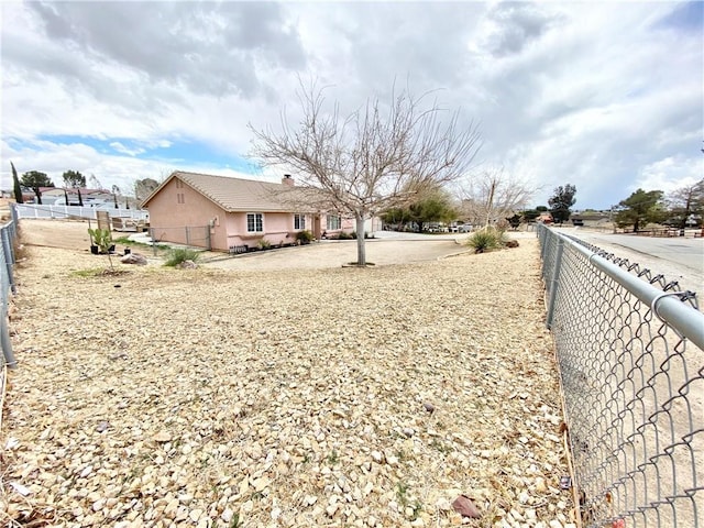 rear view of property with stucco siding, a chimney, and fence