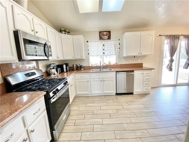 kitchen featuring white cabinetry, light stone counters, appliances with stainless steel finishes, and a sink