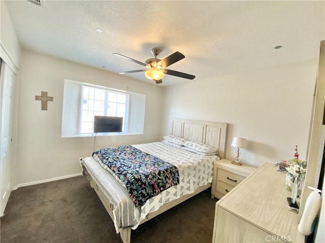 bedroom featuring a textured ceiling, baseboards, dark carpet, and ceiling fan