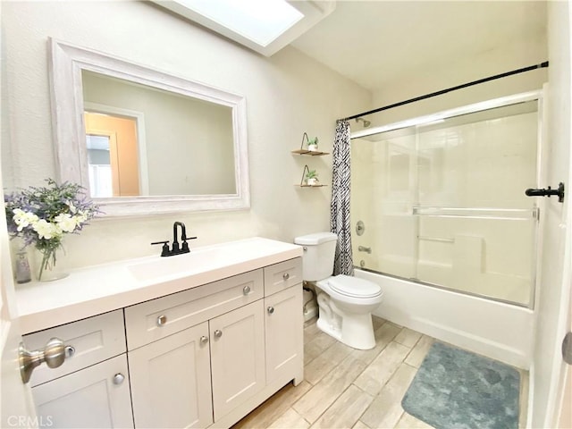 bathroom featuring wood tiled floor, toilet, shower / bath combo, a skylight, and vanity