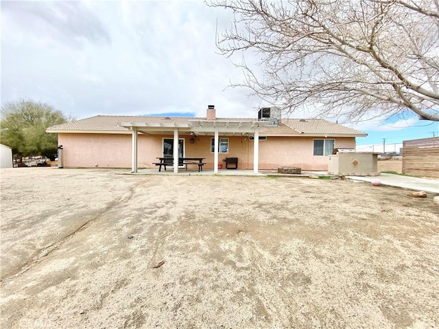 back of house featuring central AC, stucco siding, a chimney, and a patio