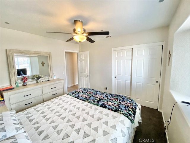 bedroom with a closet, visible vents, dark carpet, and a ceiling fan