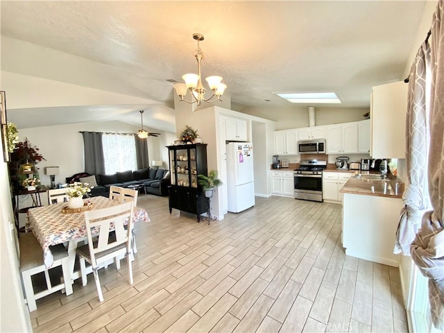 kitchen featuring lofted ceiling, appliances with stainless steel finishes, open floor plan, and white cabinets