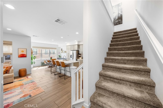 staircase featuring recessed lighting, visible vents, and wood tiled floor