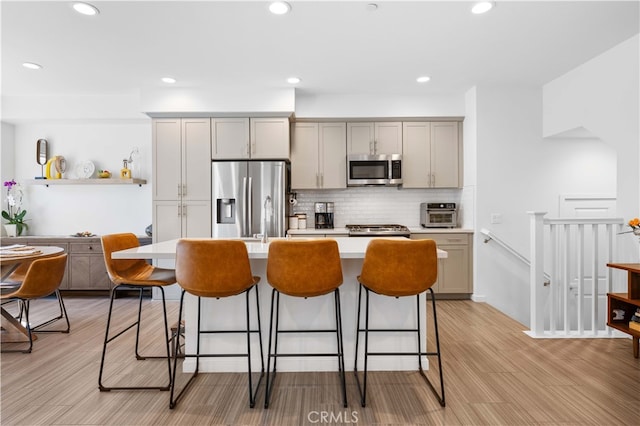 kitchen with a breakfast bar, light countertops, gray cabinetry, and stainless steel appliances