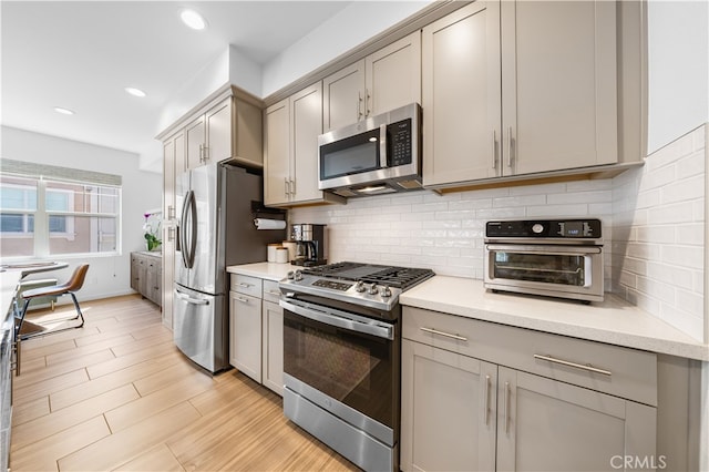 kitchen with stainless steel appliances, tasteful backsplash, gray cabinets, and light countertops