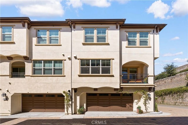 multi unit property featuring stucco siding and a garage