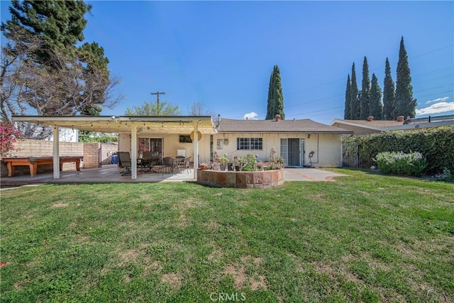 rear view of house with a yard, fence, stucco siding, and a patio area