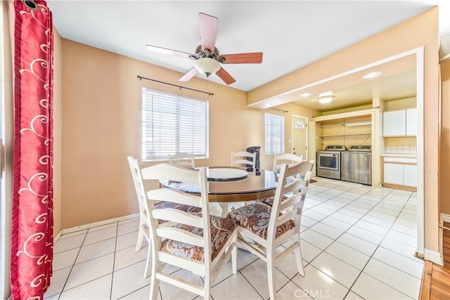 dining room featuring light tile patterned floors, a ceiling fan, baseboards, and washer and clothes dryer