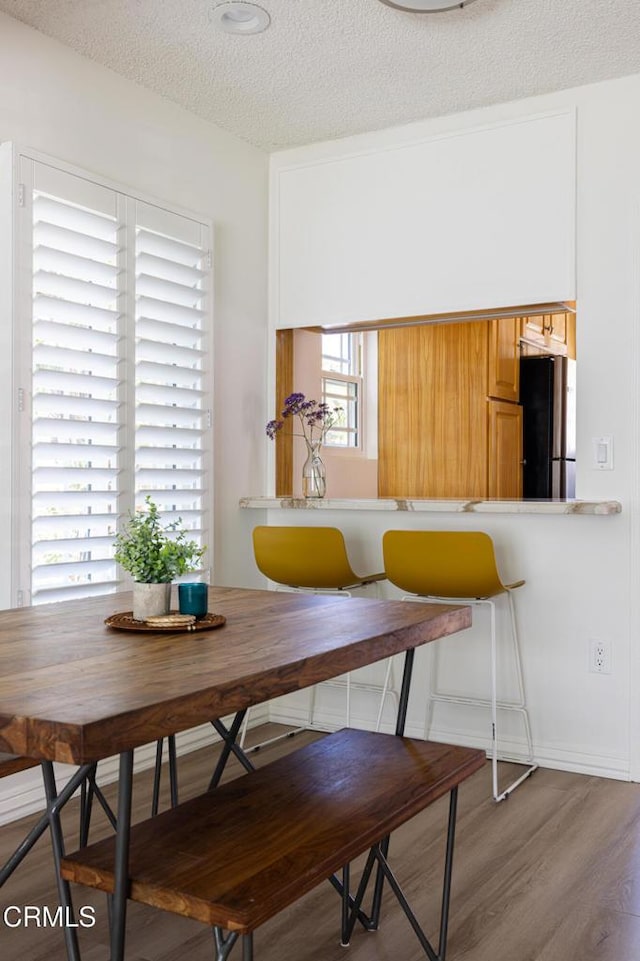 dining space with a textured ceiling, breakfast area, and wood finished floors