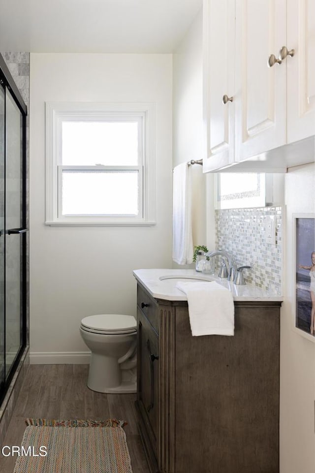 full bathroom featuring an enclosed shower, backsplash, vanity, and wood finished floors