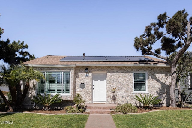 view of front of house featuring roof mounted solar panels and a front yard