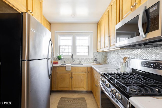 kitchen featuring a sink, decorative backsplash, appliances with stainless steel finishes, and light tile patterned floors