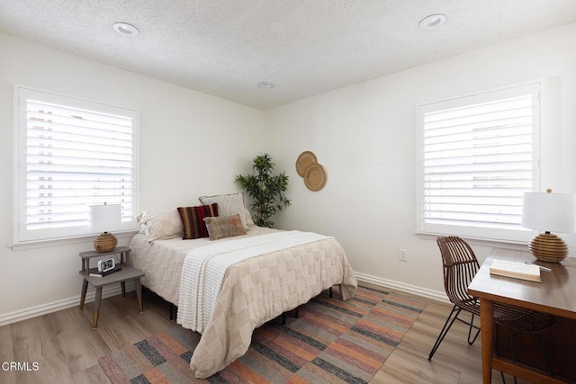 bedroom with recessed lighting, wood finished floors, baseboards, and a textured ceiling