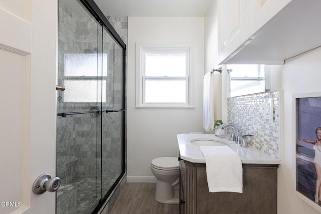 full bath with a wealth of natural light, toilet, a shower stall, and vanity