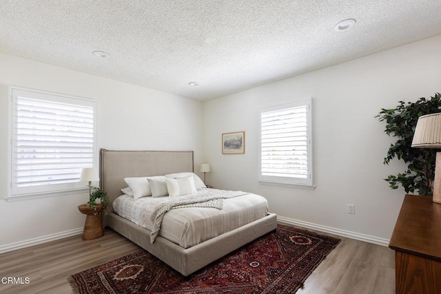 bedroom featuring multiple windows, wood finished floors, and baseboards