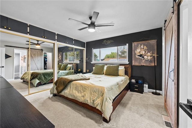 bedroom with a barn door, a ceiling fan, visible vents, and carpet floors