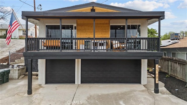 rear view of house featuring concrete driveway, a garage, and fence