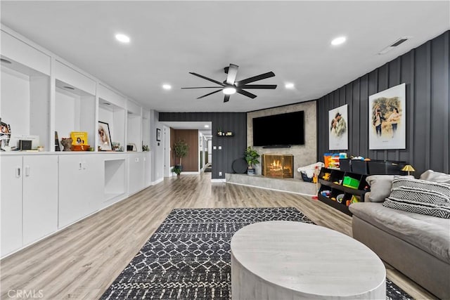 living area with light wood-type flooring, visible vents, recessed lighting, a large fireplace, and ceiling fan