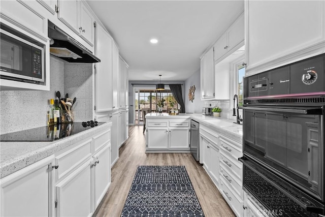 kitchen with backsplash, black appliances, under cabinet range hood, light wood-type flooring, and white cabinetry