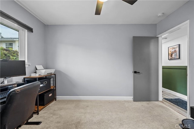 carpeted office space with a ceiling fan and baseboards