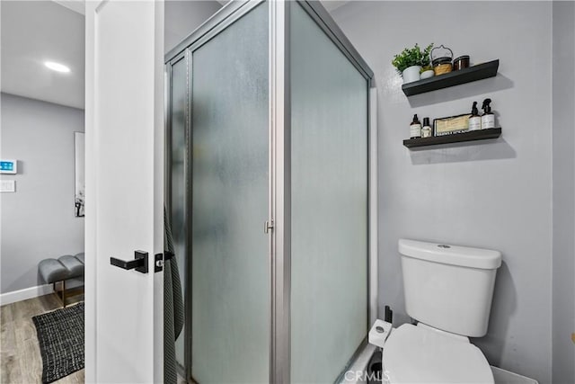 bathroom featuring a stall shower, toilet, and wood finished floors