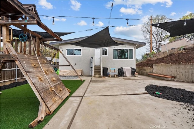 rear view of property featuring stucco siding, entry steps, a carport, and a patio area